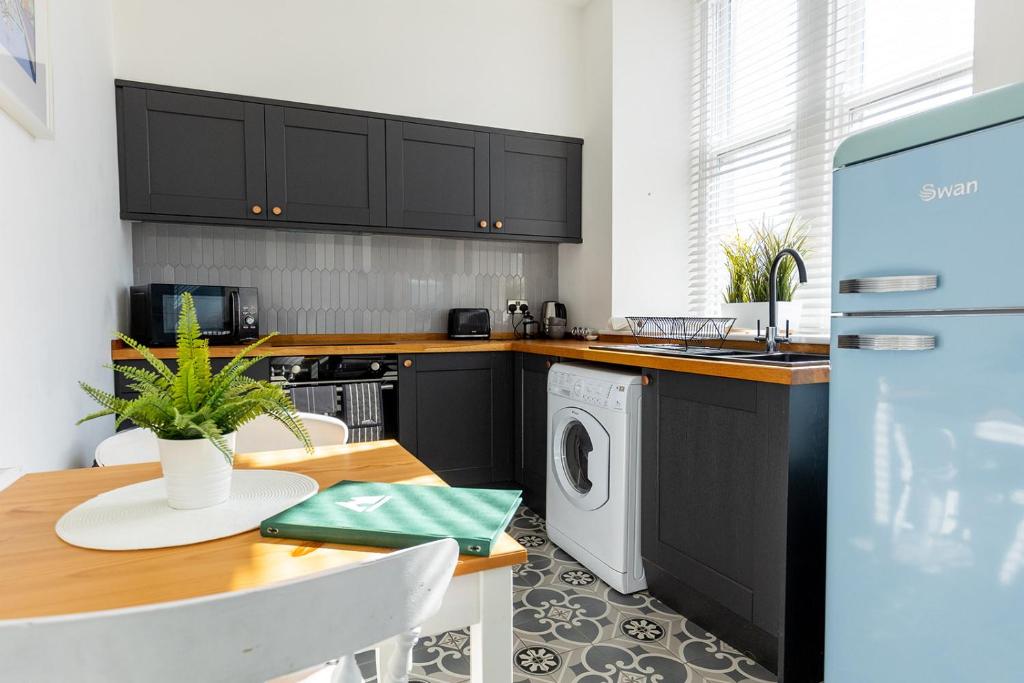 a kitchen with a table and a washing machine at ST MARYS APARTMENT - Modern Apartment in Charming Market Town in the Peak District in Penistone