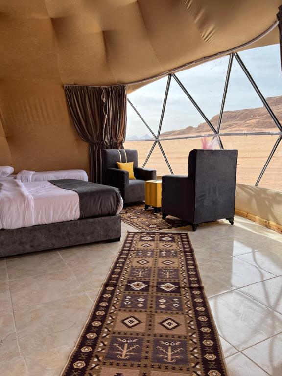 a bedroom with a bed and a chair and a rug at Moon Magic Valley in Wadi Rum