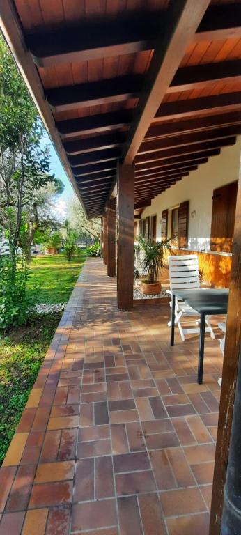 un patio con un banco bajo un techo de madera en Elisa Holidays Apartments, en Puegnago sul Garda