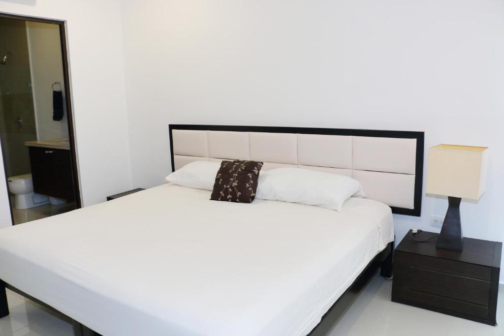 um quarto com uma cama branca e uma cabeceira preta em Marina Excelsior em Playa del Carmen