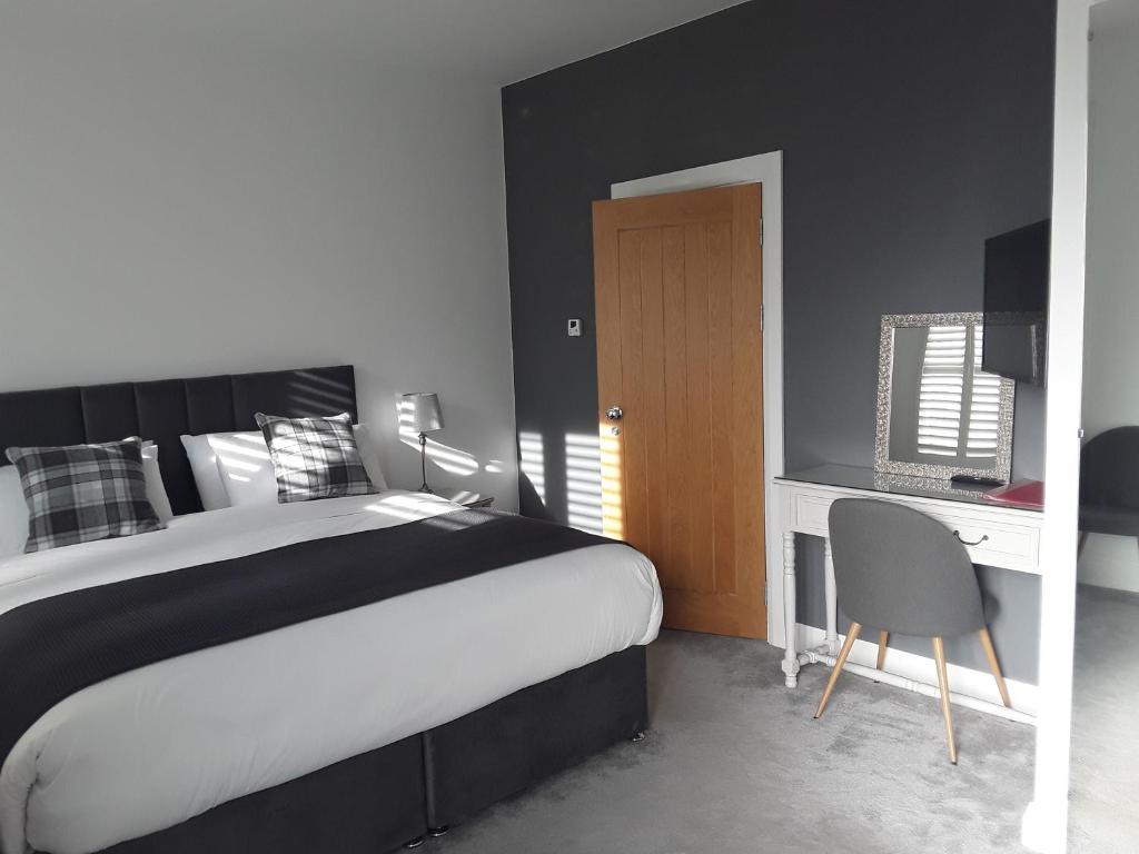 a bedroom with a bed and a desk with a chair at Pairc Na Coille Killarney in Killarney