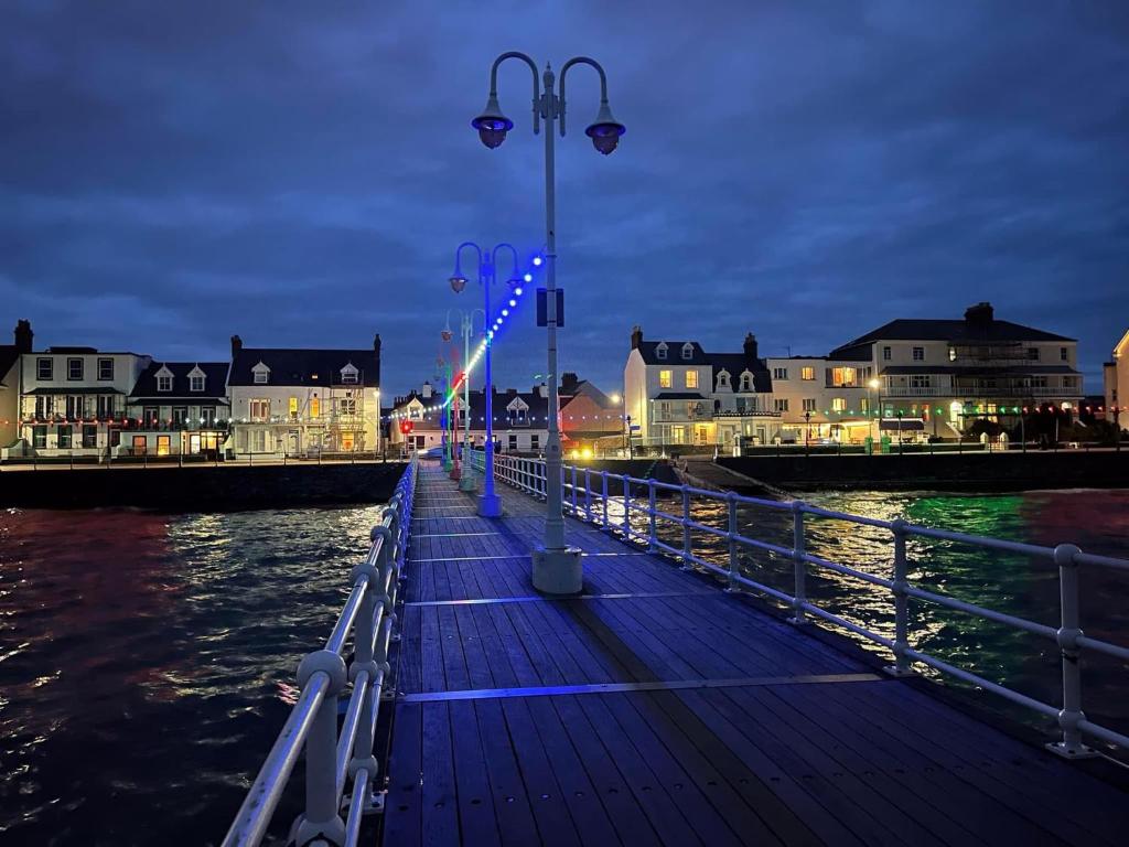 a dock with lights on the water at night at De L'Etang in Saint Helier Jersey