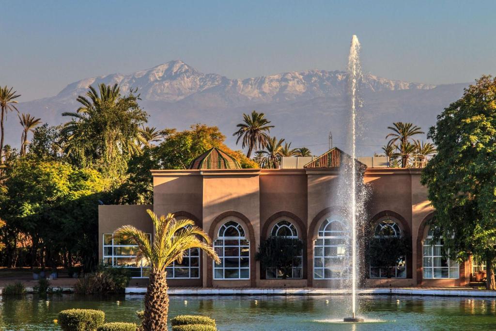 een fontein voor een gebouw met bergen op de achtergrond bij Barceló Palmeraie in Marrakesh