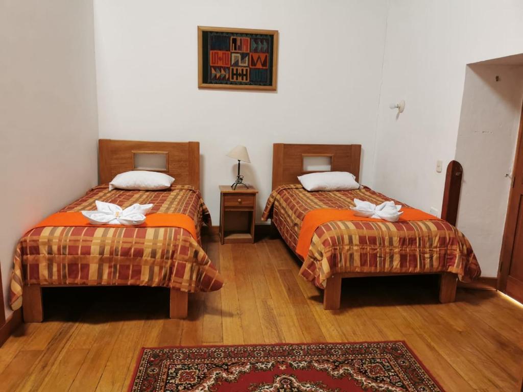 a hotel room with two beds and a rug at Casa San Pedro Cusco in Cusco