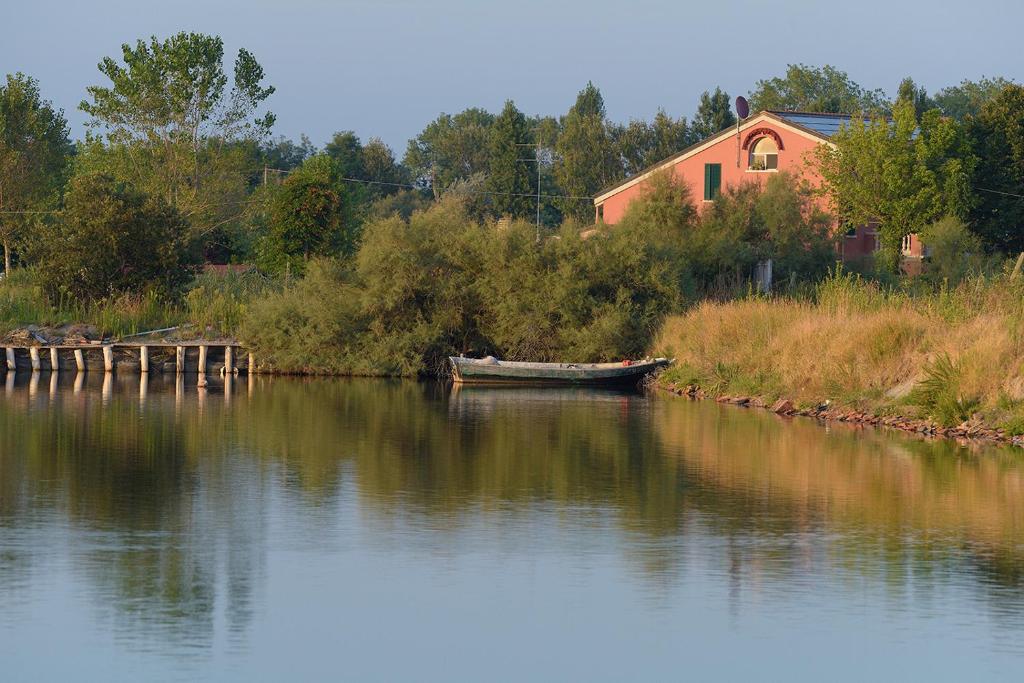 a boat sitting on the water next to a house at Residenza le Saline in Comacchio