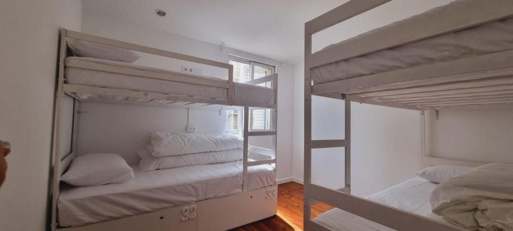 two bunk beds in a room with a window at Owls Hostel Ribeiro in Porto