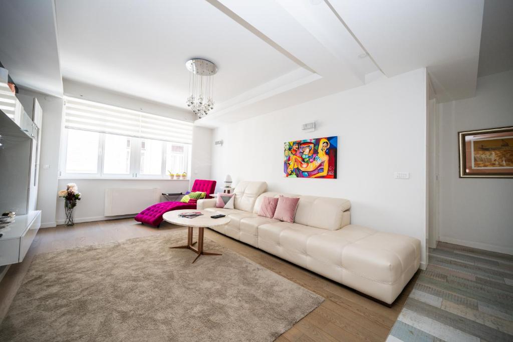 Biały salon z białą kanapą i różowymi akcentami w obiekcie Modern Apartment In City Center w Sarajewie
