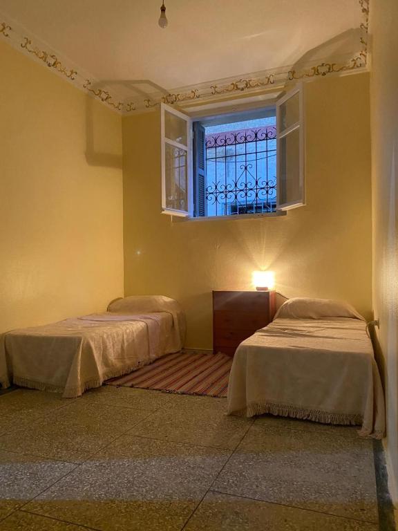 two beds in a room with a window at La casita de Larache in Larache