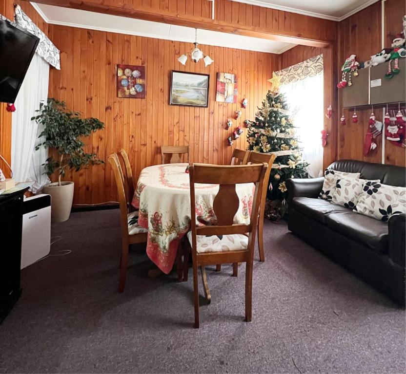 sala de estar con mesa, sofá y árbol de Navidad en Hostal Feliza en Valdivia