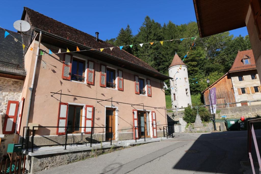 un edificio con ventanas de contraventanas rojas y una torre de reloj en Les Postillons en Chartreuse en Saint-Pierre-dʼEntremont