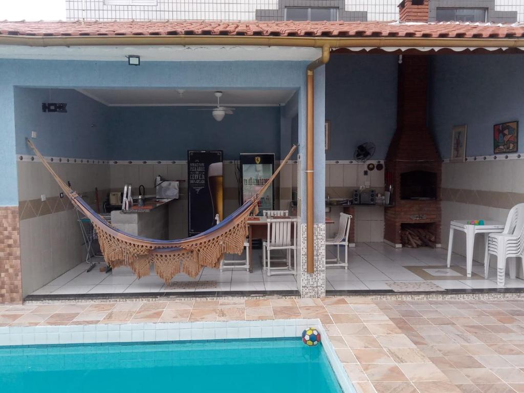 a patio with a hammock next to a pool at Pousada Aconchego na Praia in Praia Grande