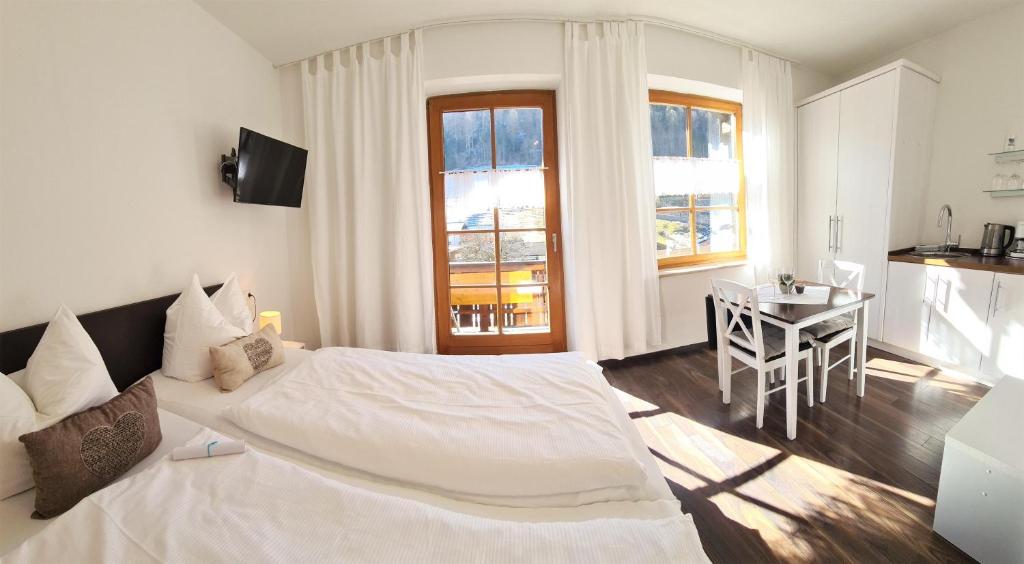 Un dormitorio blanco con una cama grande y una mesa en Gästehaus Sieger-Brandner Apartment im Gästehaus Sieger-Brandner, en Ramsau