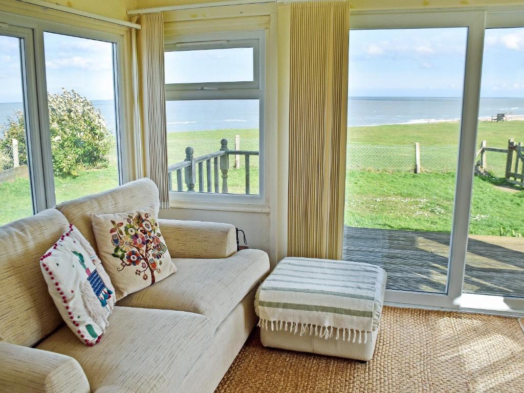 sala de estar con sofá y vistas al océano en Bacton Seaview Bungalow, en Bacton