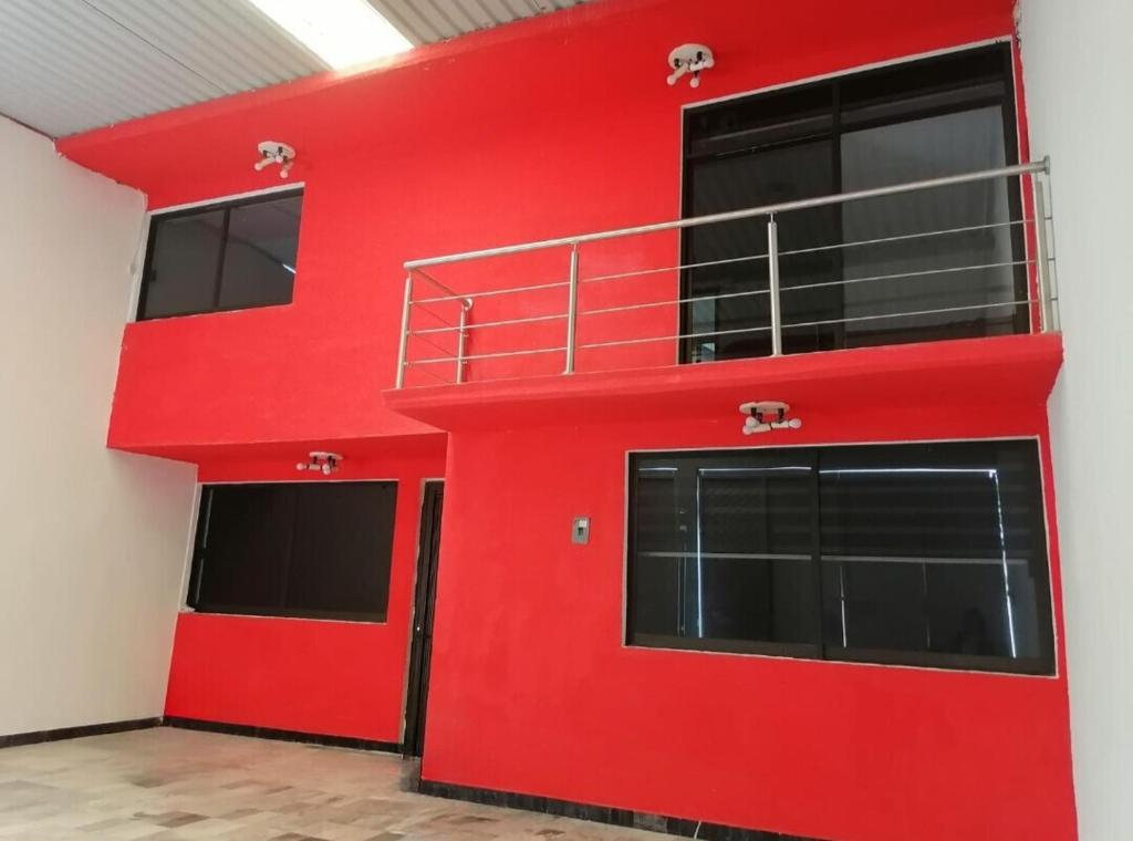een rood gebouw met twee garagedeuren en een balkon bij Hogar amplio y acogedor in Ixmiquilpan