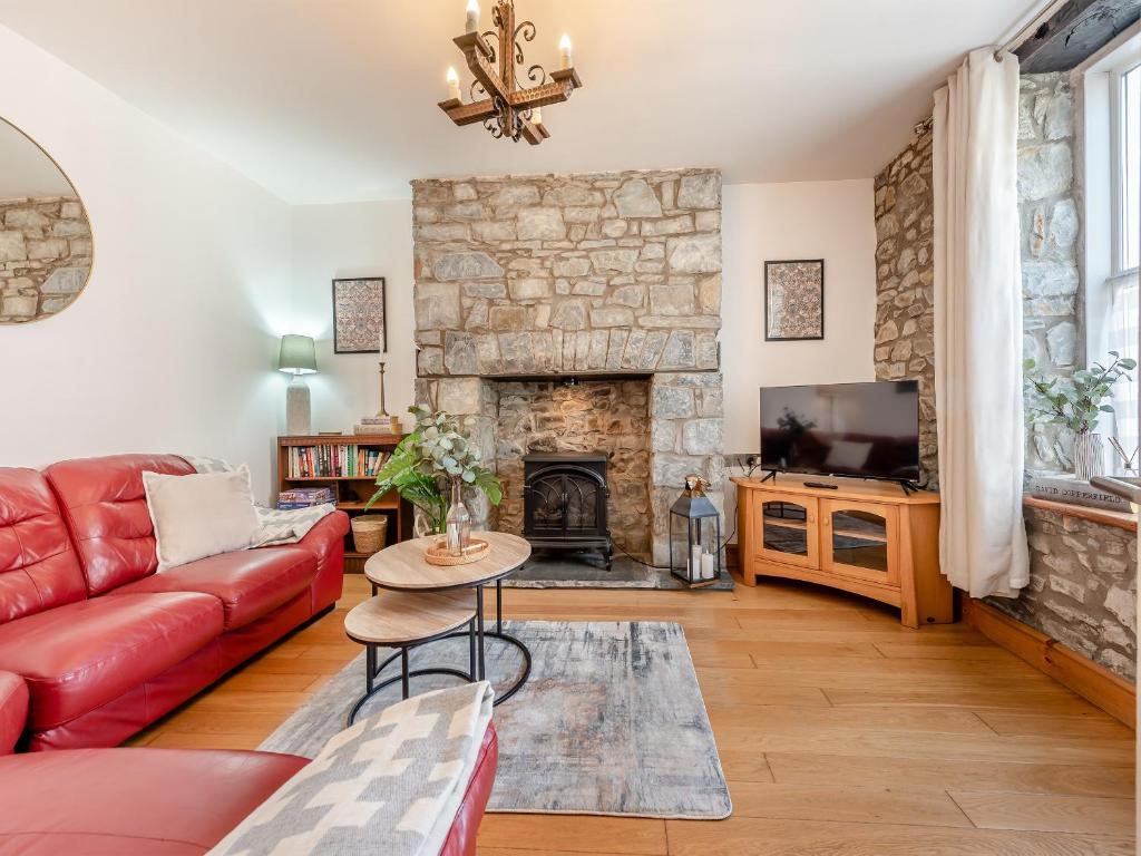a living room with a red couch and a fireplace at Gwynfor in New Quay