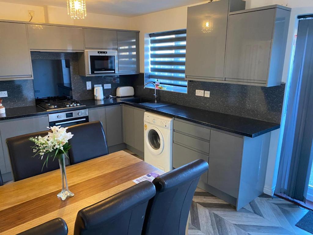 Oasis Abode @ Ashover Newcastle في Kenton: مطبخ مع طاولة خشبية مع كراسي وغرفة طعام