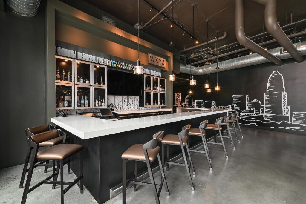 a bar with a long counter and chairs in a room at Aloft Charlotte City Center in Charlotte