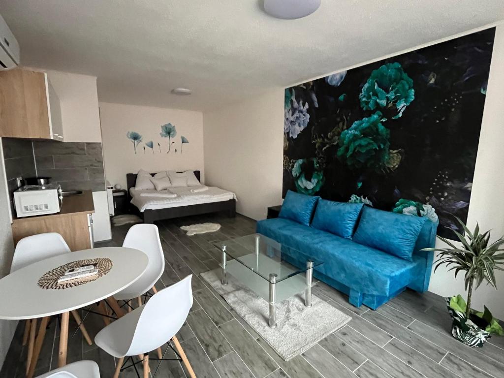 een woonkamer met een blauwe bank en een tafel bij Habán Lux Apartmanház in Hévíz