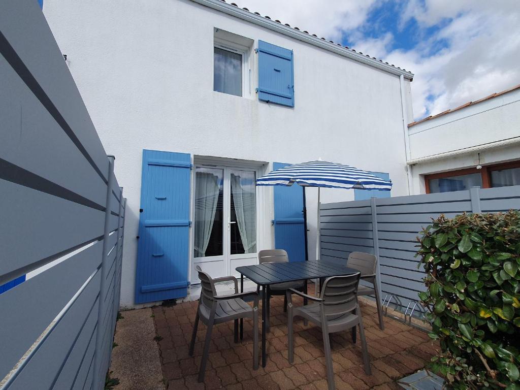 eine Terrasse mit einem Tisch, Stühlen und einem Sonnenschirm in der Unterkunft Maison La Faute-sur-Mer, 2 pièces, 4 personnes - FR-1-476-21 in La Faute-sur-Mer