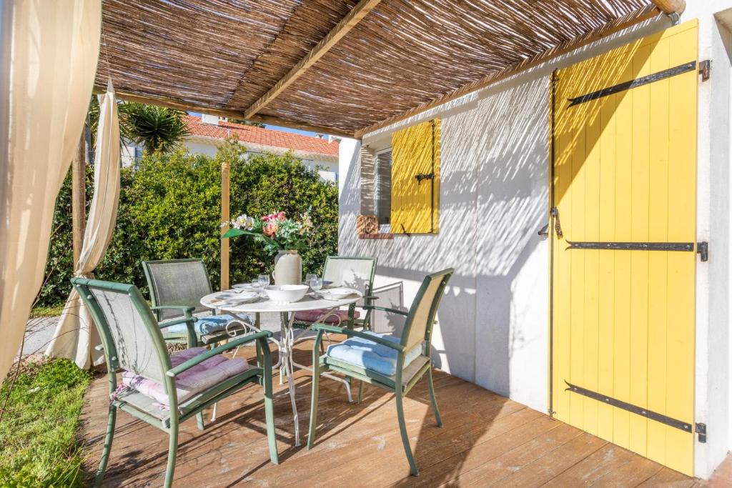 d'une terrasse avec une table et des chaises ainsi qu'une porte jaune. dans l'établissement Maison des Lilas - Welkeys, à La Seyne-sur-Mer