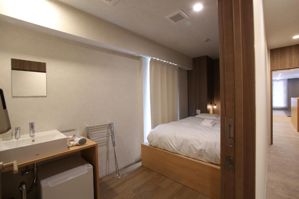 a bathroom with a bed and a sink in a room at OHWA hostel minowa station in Tokyo