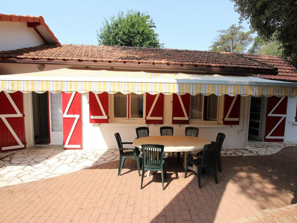 un patio avec une table et des chaises et un bâtiment dans l'établissement Maison traditionnelle à Saint Brevin, 850m plage, lumineux séjour, jardin, 4 ch., garage, animaux OK - FR-1-364-66, à Saint-Brévin-les-Pins