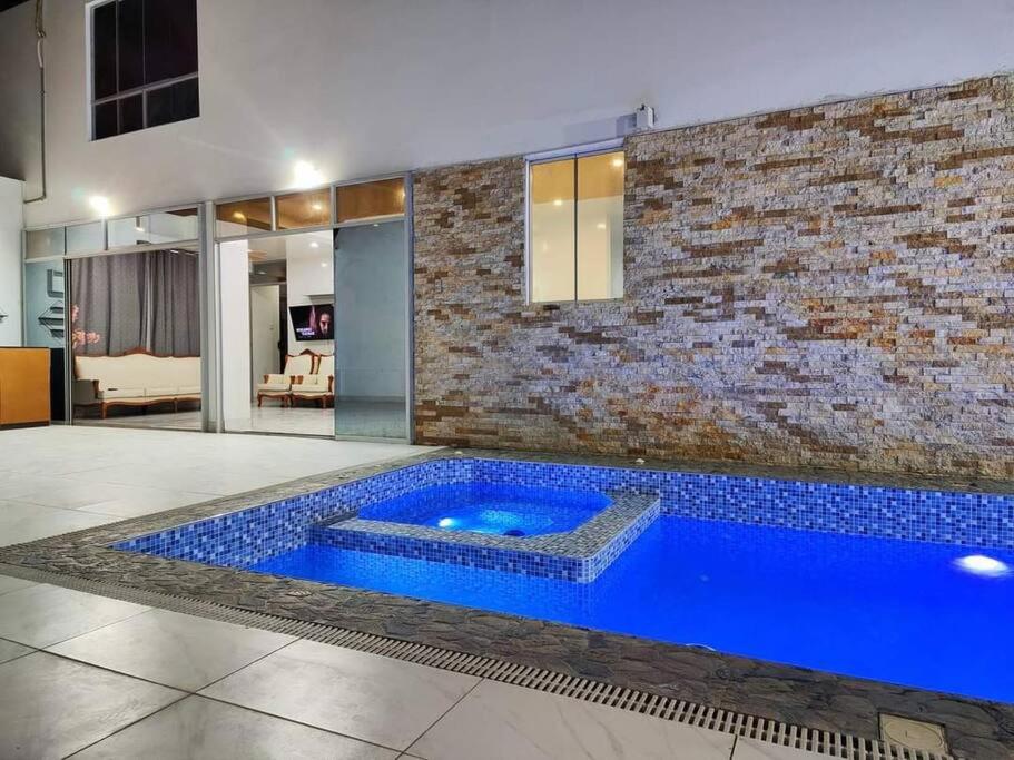 uma grande piscina azul num quarto com uma parede de tijolos em Casa Privada de Estreno con Piscina en Ica em Ica