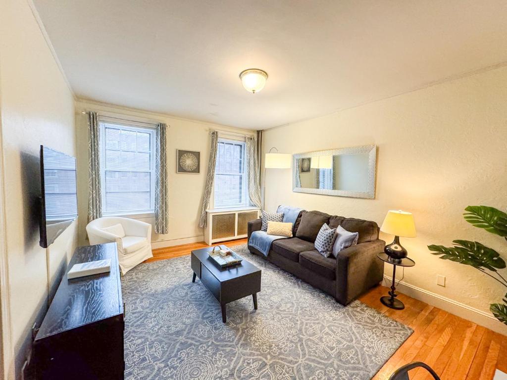 a living room with a couch and a table at Sun-filled 1bed, Corner Unit W Pool In Com Ave in Boston