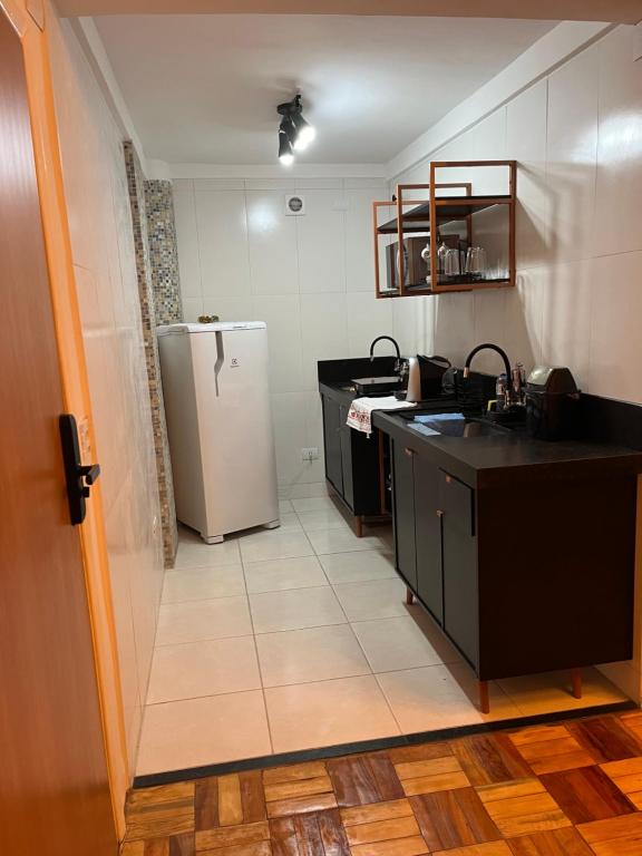 a kitchen with a refrigerator and a tile floor at Conforto e aconchego in Poços de Caldas