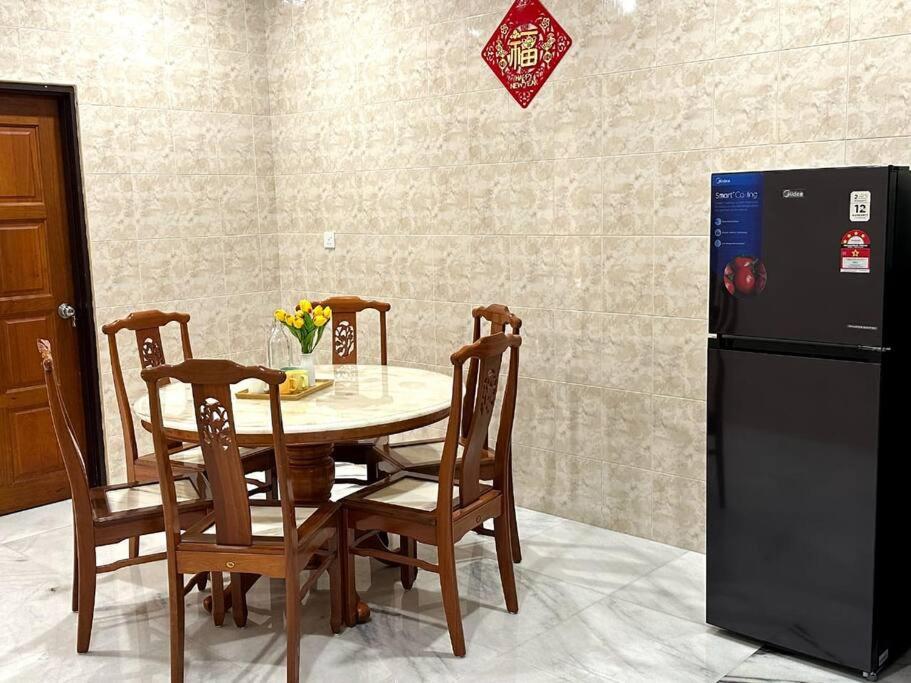 uma sala de jantar com uma mesa e um frigorífico em Cozy 2StoreyHome 5Room11Pax@ChaiLengPark em Perai