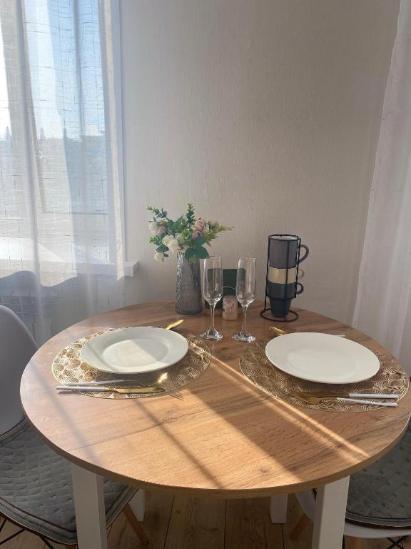 a wooden table with two plates and wine glasses at 1кмн Квартира по проспекту Республика 30 in Astana