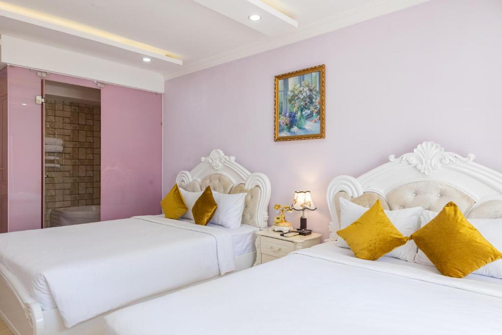 two beds in a bedroom with white and yellow pillows at Happy Star Hotel Nha Trang in Nha Trang