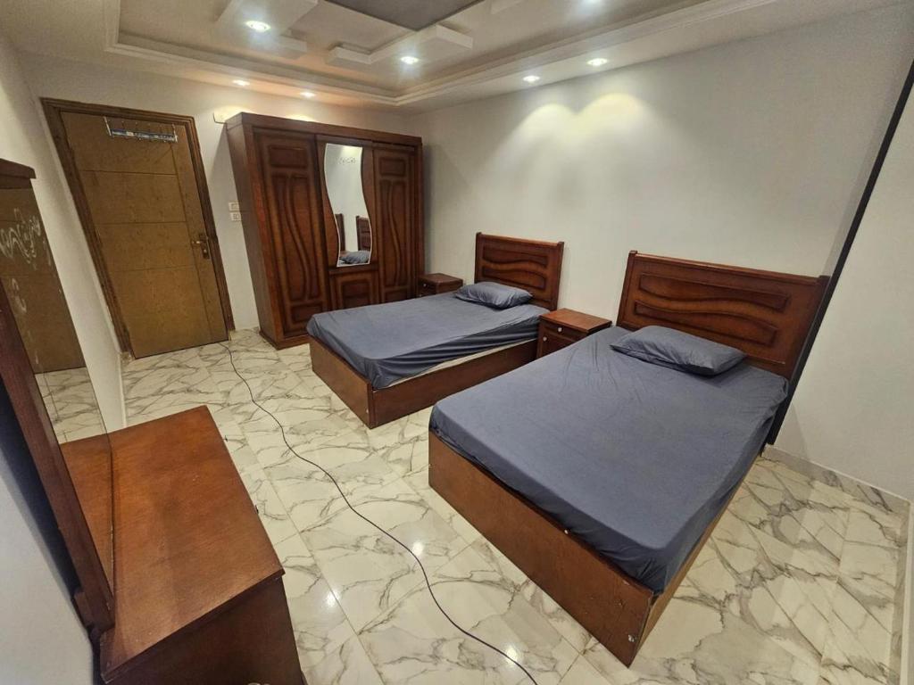 Cette chambre comprend 2 lits et un miroir. dans l'établissement شقة مودرن للايجار اليومي والاسبوعي, à Mansoura