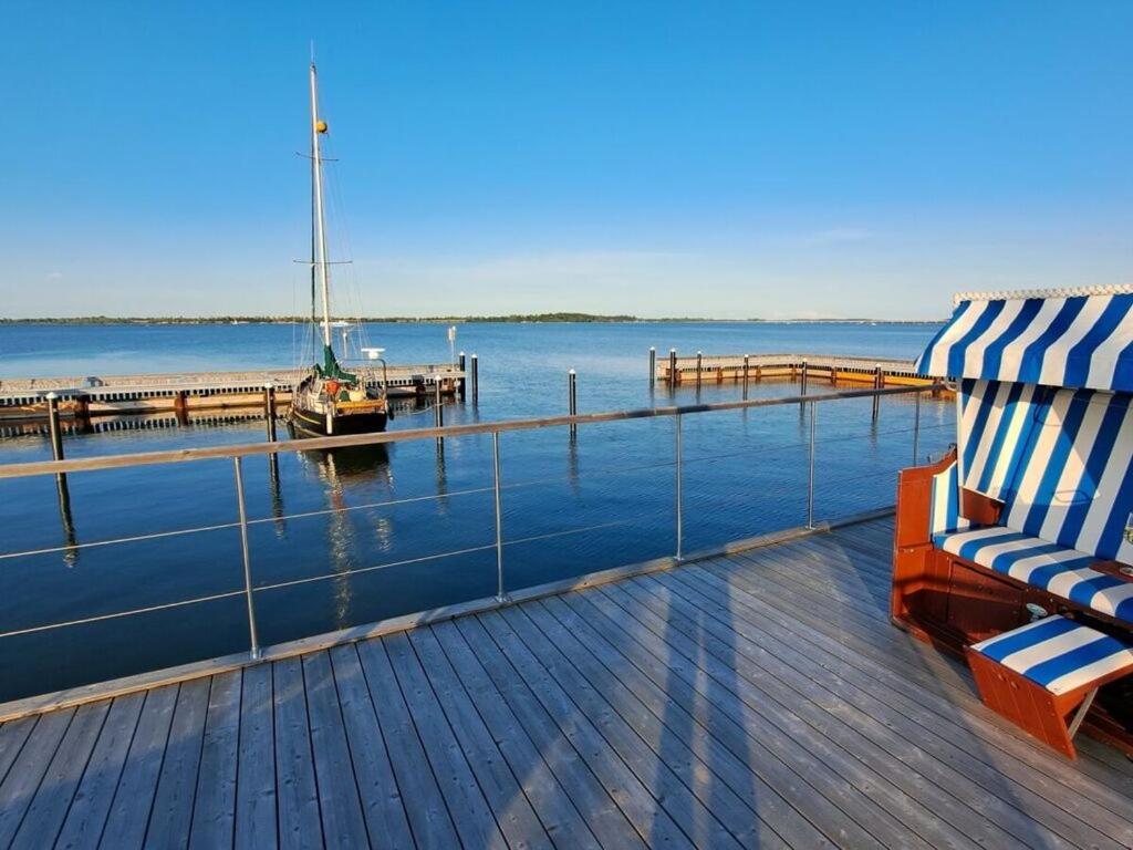 a deck with a chair and a boat on the water at Houseboat Harmony in Stralsund