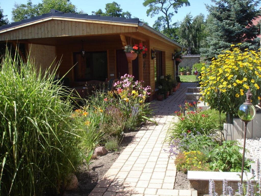 un jardin avec une maison fleurie et une passerelle dans l'établissement "Am Barschsee" Modern retreat, 