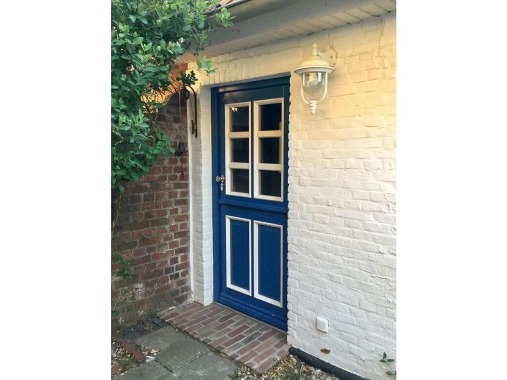 una puerta azul en el lateral de una casa en Haus Am Deich Modern retreat, en Cadenberge