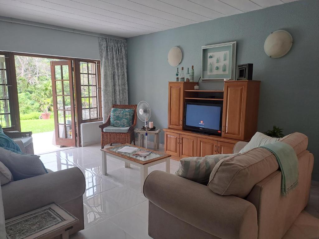 a living room with two couches and a tv at Eden Wilds 6 Paradise on Umtavuna River in Port Edward