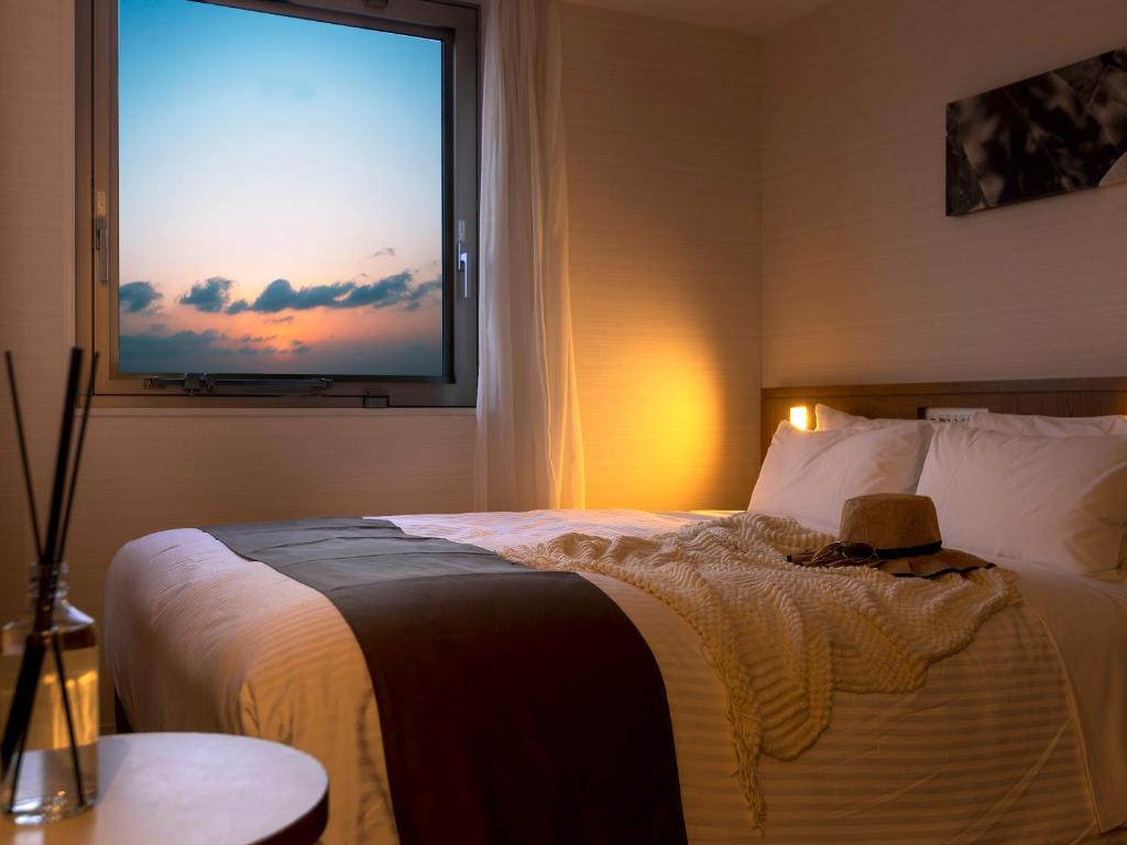 那覇市にあるホテルグレイスリー那覇のベッドルーム1室(ベッド1台、大きな窓付)