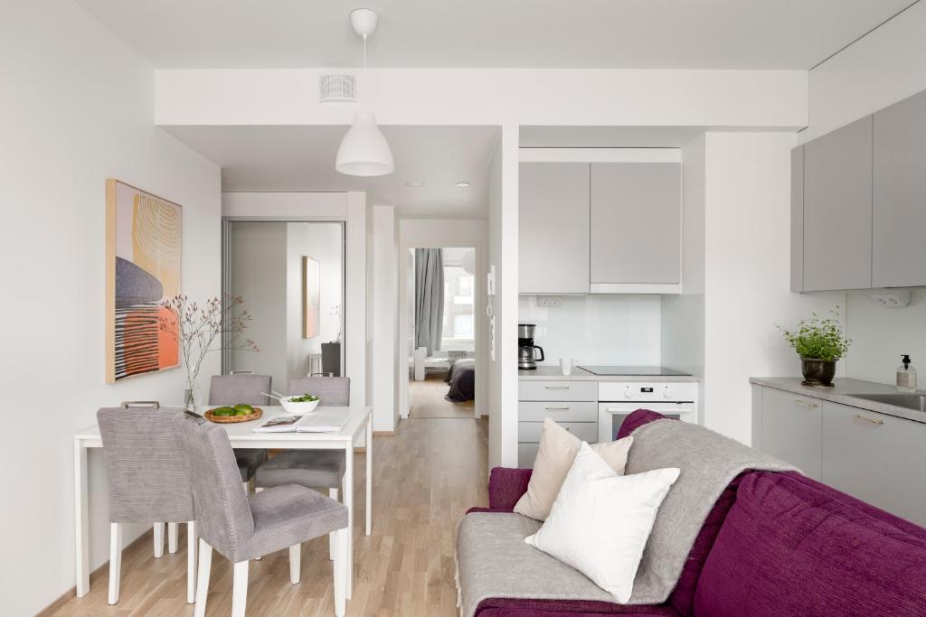 uma sala de estar e cozinha com um sofá e uma mesa em 2BR design home 400 m from train station Tikkurila em Vantaa