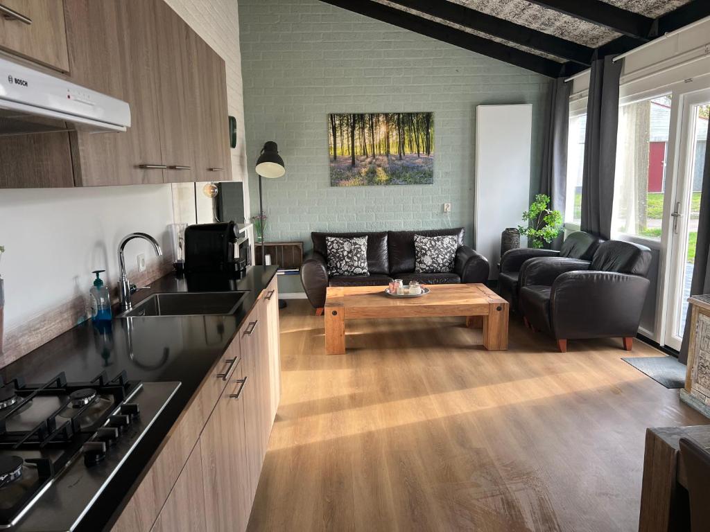 een keuken en een woonkamer met een bank en een tafel bij Gehele Bungalow Simpelveld op een park in Simpelveld