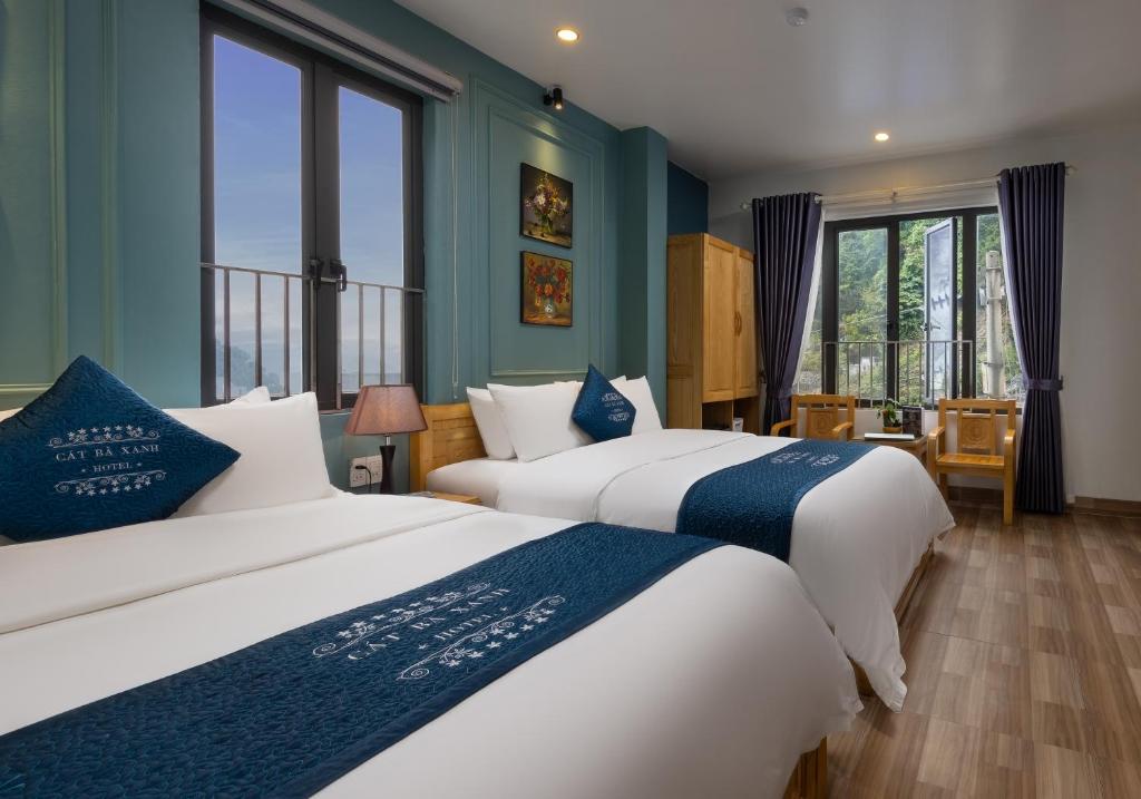 2 łóżka w pokoju z niebieskimi ścianami i oknami w obiekcie Cat Ba Xanh Spring Garden Hotel w mieście Cát Bà