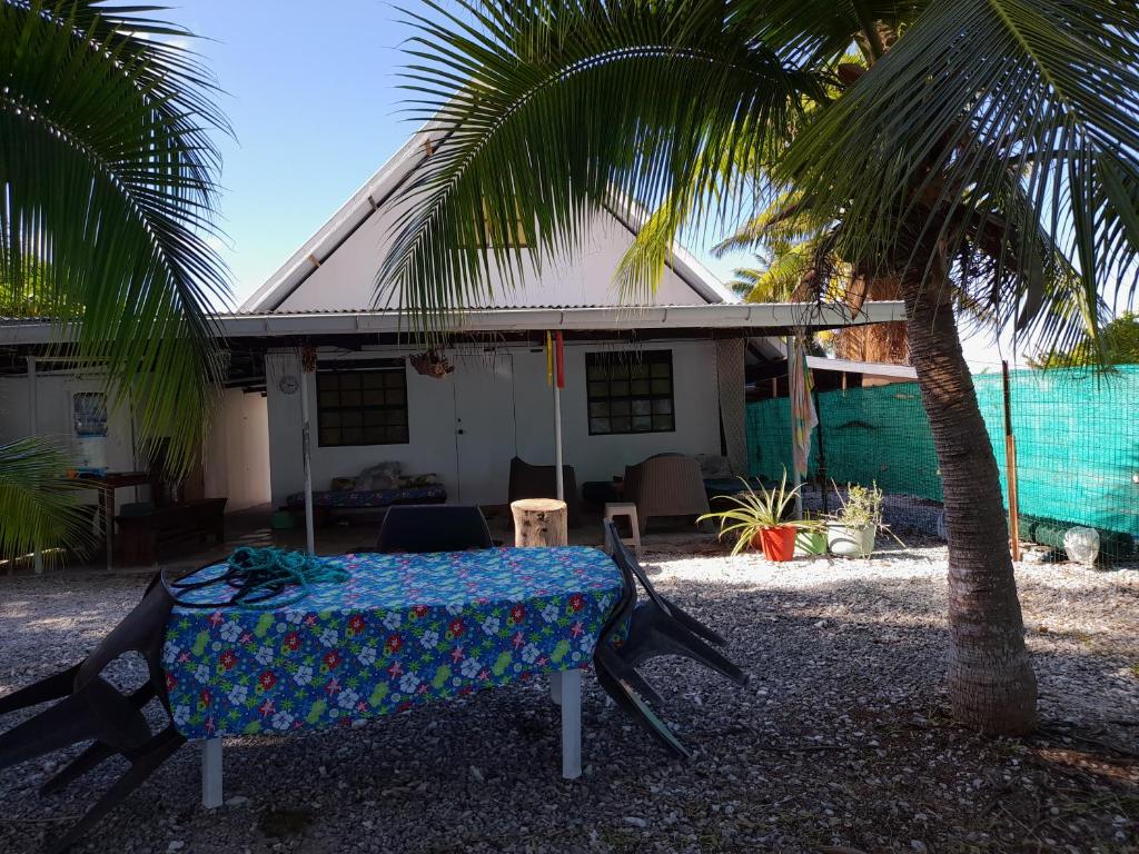 une table devant une maison avec un palmier dans l'établissement HINAMOE LODGE, à Avatoru