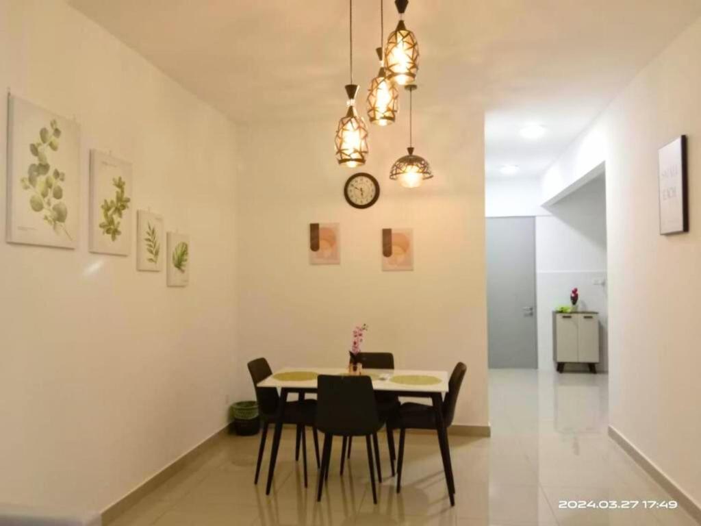 une salle à manger avec une table, des chaises et une horloge dans l'établissement Bayu Temaing Residence - Eco Friendly Retreat, à Seremban