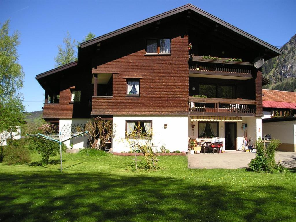 ein großes Backsteinhaus mit grünem Rasen davor in der Unterkunft Landhaus Schanzblick in Bad Hindelang