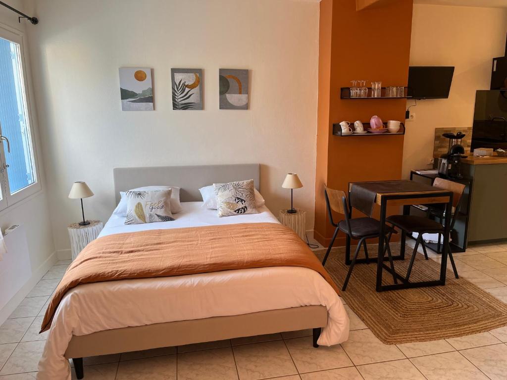 een slaapkamer met een bed, een tafel en een bureau bij L'enclos bleu, vendée sud, marais poitevin in Chaillé-les-Marais