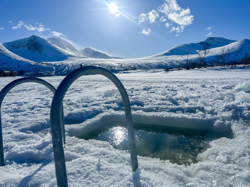a hole in the snow with mountains in the background at Fairytale STAYcation - JACUZZI, BOAT & SAUNA in Bjørkli