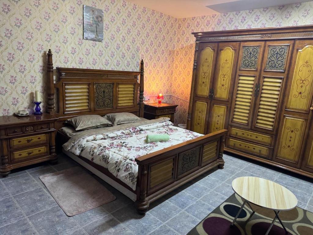 een slaapkamer met een groot bed en houten meubilair bij العين الهيلي مصباح ب 5 in Al Ain