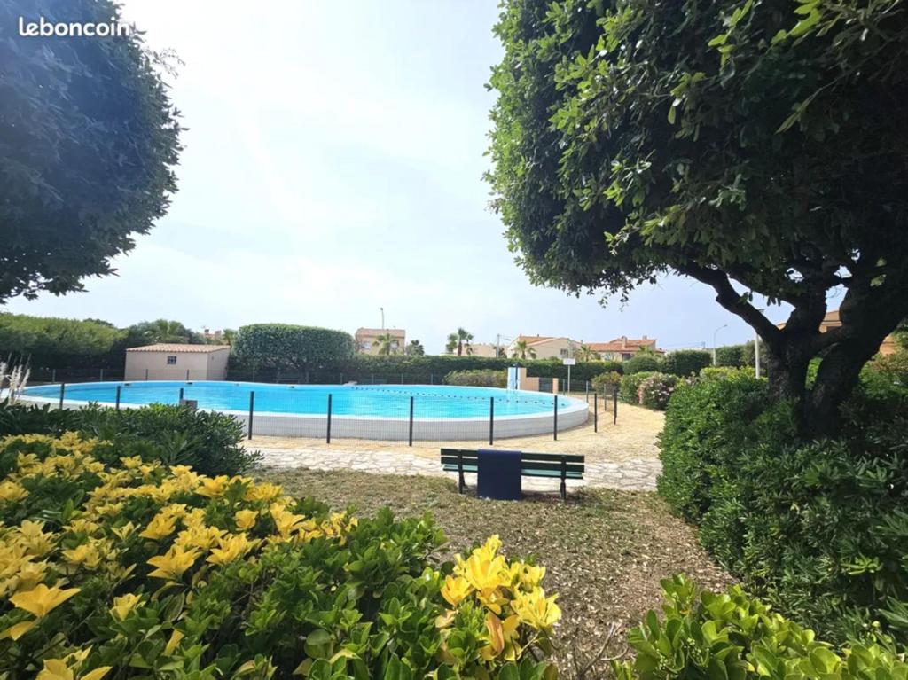 - une piscine dans un parc avec un banc et des fleurs dans l'établissement la brise du Brusc, à Six-Fours-les-Plages