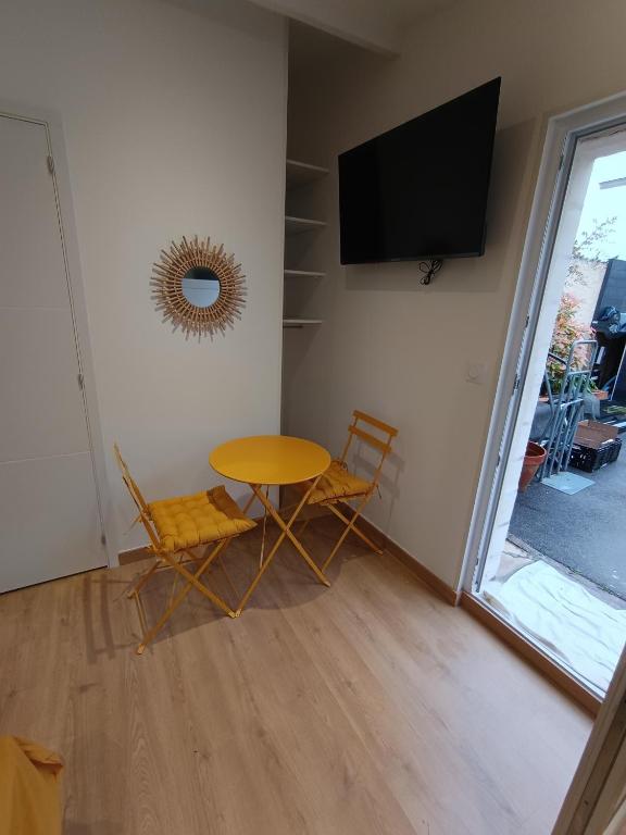 Habitación con mesa, 2 sillas y TV. en Studio neuf des amandines en Pont-Sainte-Maxence