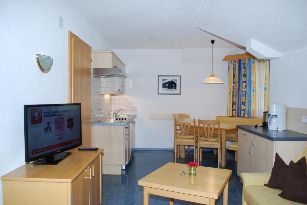 a living room with a couch and a tv and a kitchen at Chasa Monthani in Ischgl